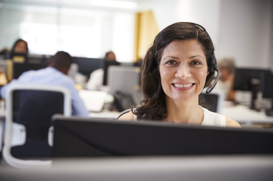 Middle aged woman working at computer with headset in office